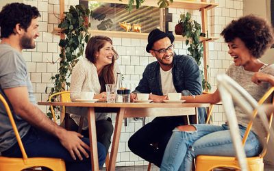 Young people having a great time in cafe. Friends smiling and sitting in a coffee shop, drinking coffee and enjoying together.